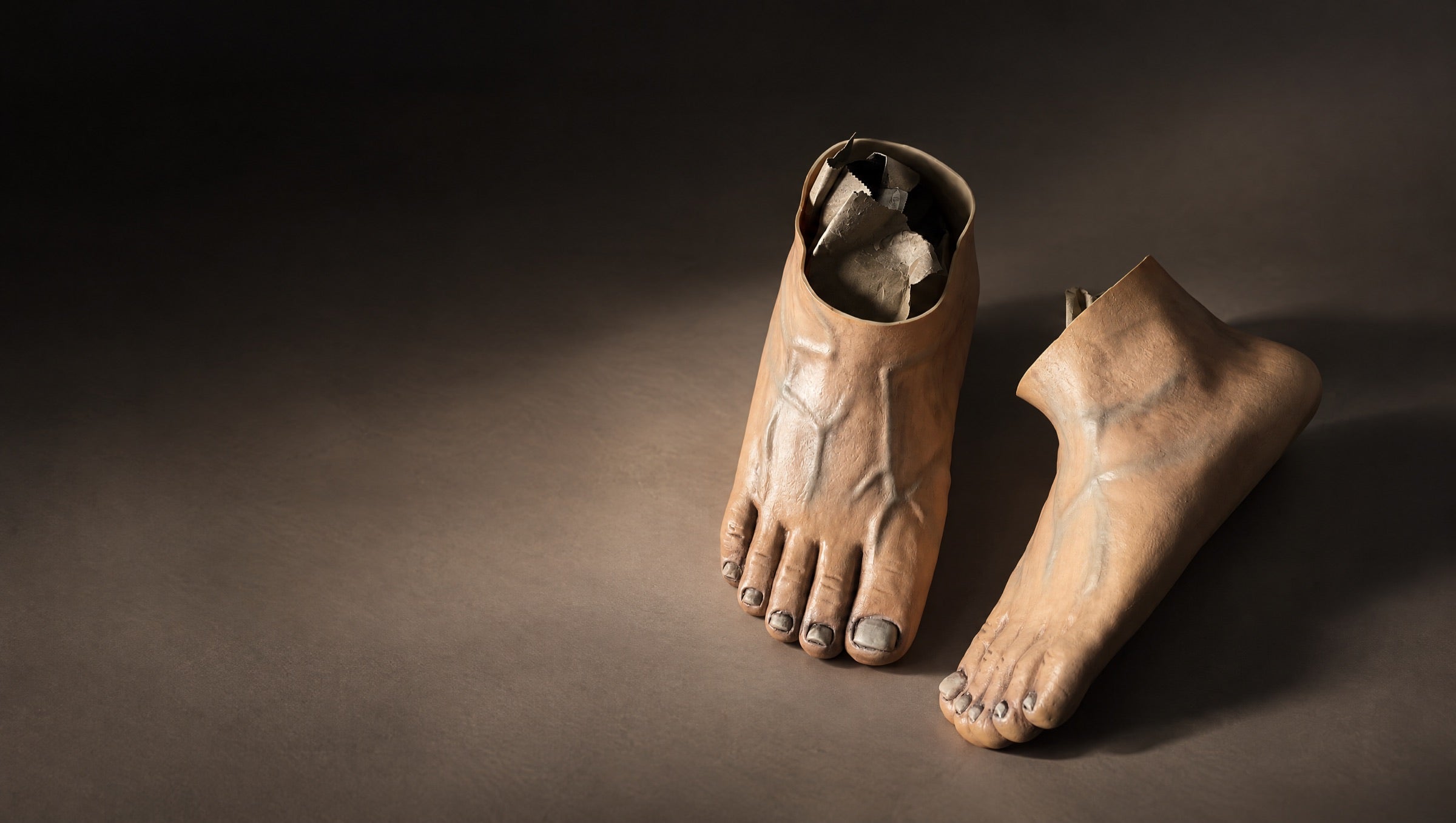 A pair of Caveman Kicks, shoes shaped like bare feet, under a spotlight